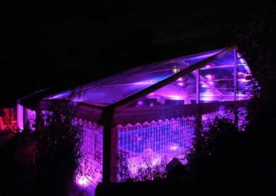 Marquee with clear PVC ceiling, doors and windows and lighted at night with purple lighting repped for party