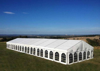 Panoramic view of white marquee, clear windows as seen from hillside looking down into valley