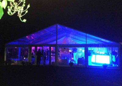 Marquee with clear PVC ceiling, doors and windows and lighted at night with blue lighting repped for party