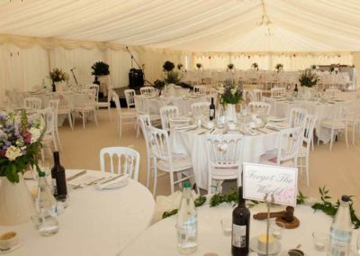 Interior wedding marquee staged for wedding and guests with cream accents and chandeliers