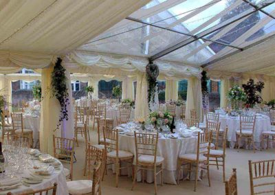 Image of a luxury marquee prepared for a wedding with beautiful table settings, tiny lights in the roof and a transparent section of roof to bring light into the marquee