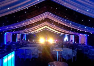 Marquee dressed for Corporate Christmas party, high cocktail table, round dinner tables, blue lighting, sparkling ceiling lights, banquet chairs