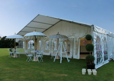 Image of marquee with front veranda, patio tables, chairs and sun umbrella